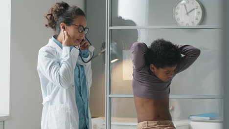 Female-Pediatrician-Checking-Lungs-of-African-American-Boy-with-Stethoscope