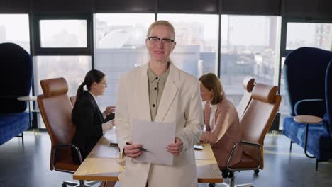 Portrait-Confident-middle-aged-businesswoman-with-glasses-in-a-white-suit-holding-a-sheet-of-paper-in-her-hands-while-working-in-the-office-Near-the-table