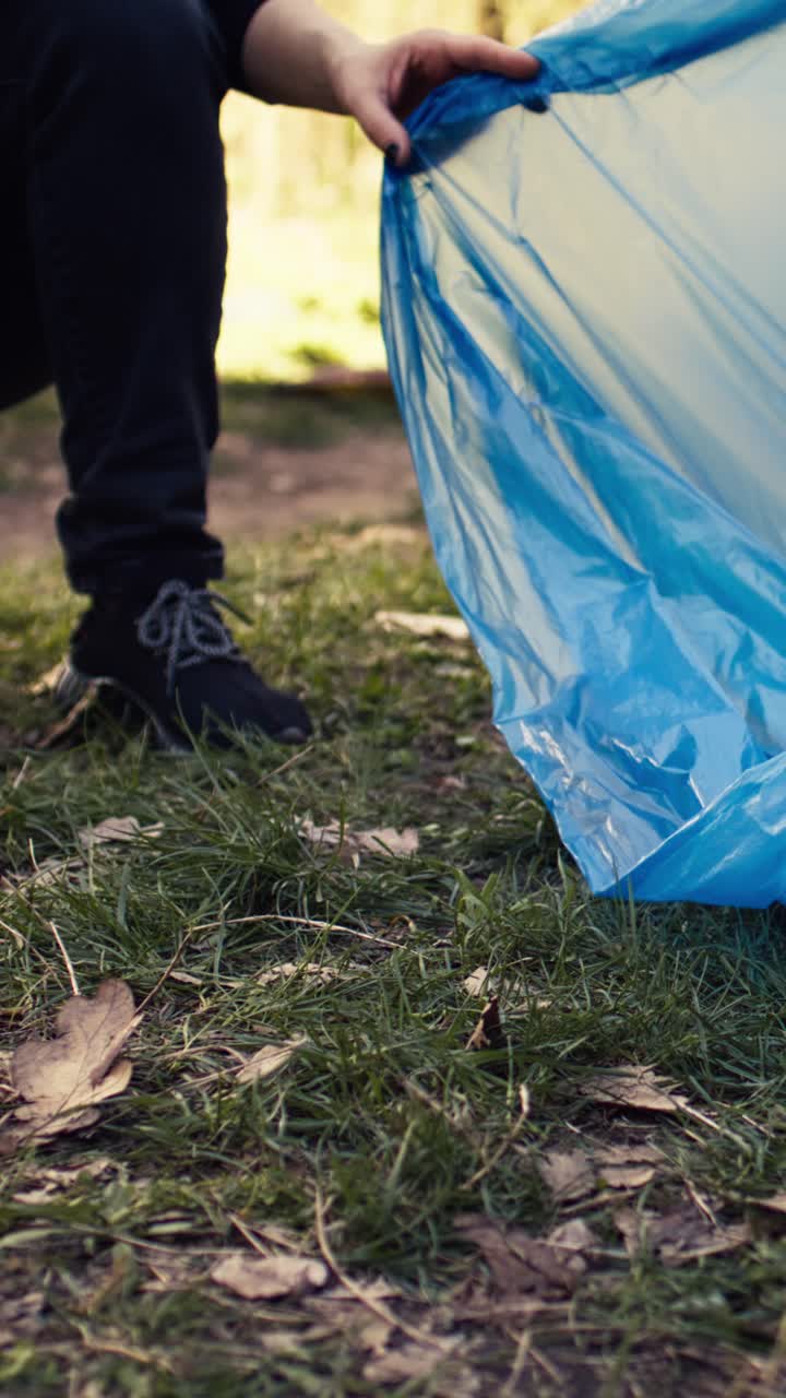 Primo piano di mani che raccolgono rifiuti di plastica in un parco