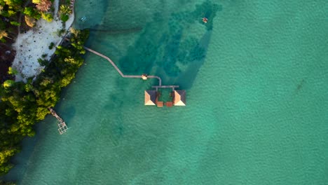 Vista-De-Arriba-Hacia-Abajo-De-Un-Complejo-Con-Un-Embarcadero-De-Madera-En-Medio-Del-Mar-En-La-Isla-Leebong-En-Belitung,-Indonesia