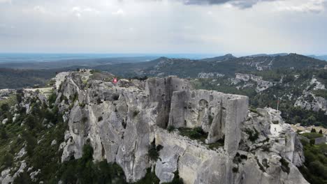 Stark-grey-white-castle-ruins-on-top-of-epic-cliffs-in-Les-Baux-de-Provence-France,-aerial-overview