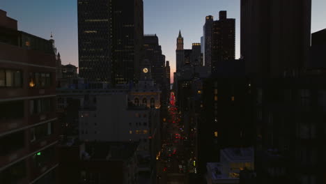 Volar-Entre-Los-Rascacielos-Del-Centro-Después-Del-Atardecer.-Calle-Muy-Transitada-Con-Luces-Traseras-Rojas.-Manhattan,-Ciudad-De-Nueva-York,-Estados-Unidos