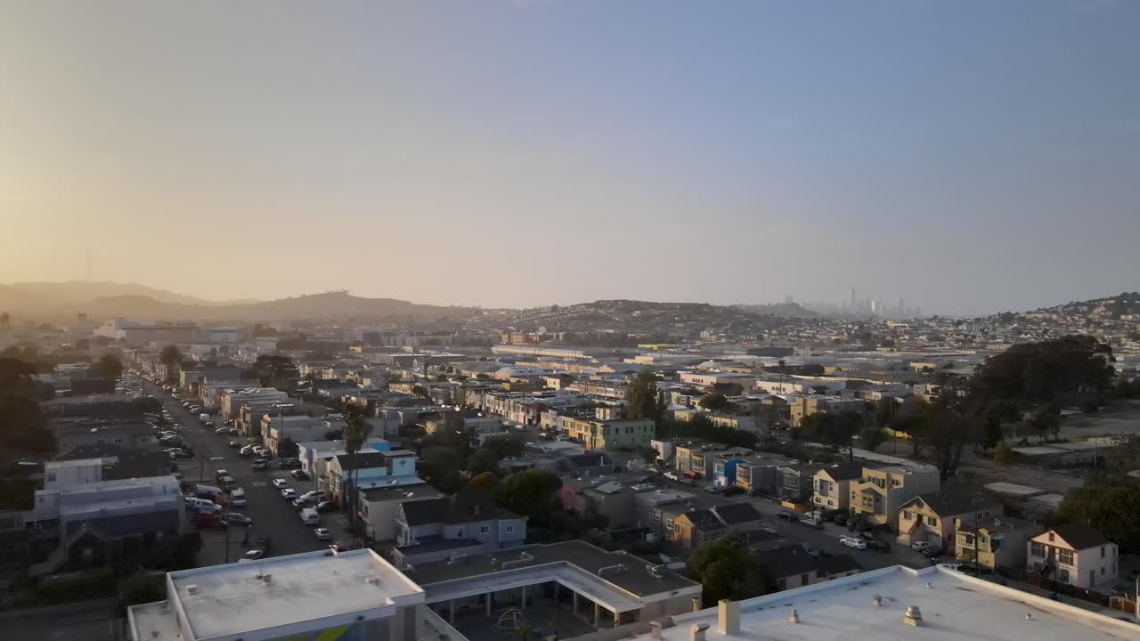As the sun sets, this drone footage offers a breathtaking flyover of San Francisco's Bayview neighborhood, with the city's resplendent downtown skyline elegantly framed in the background