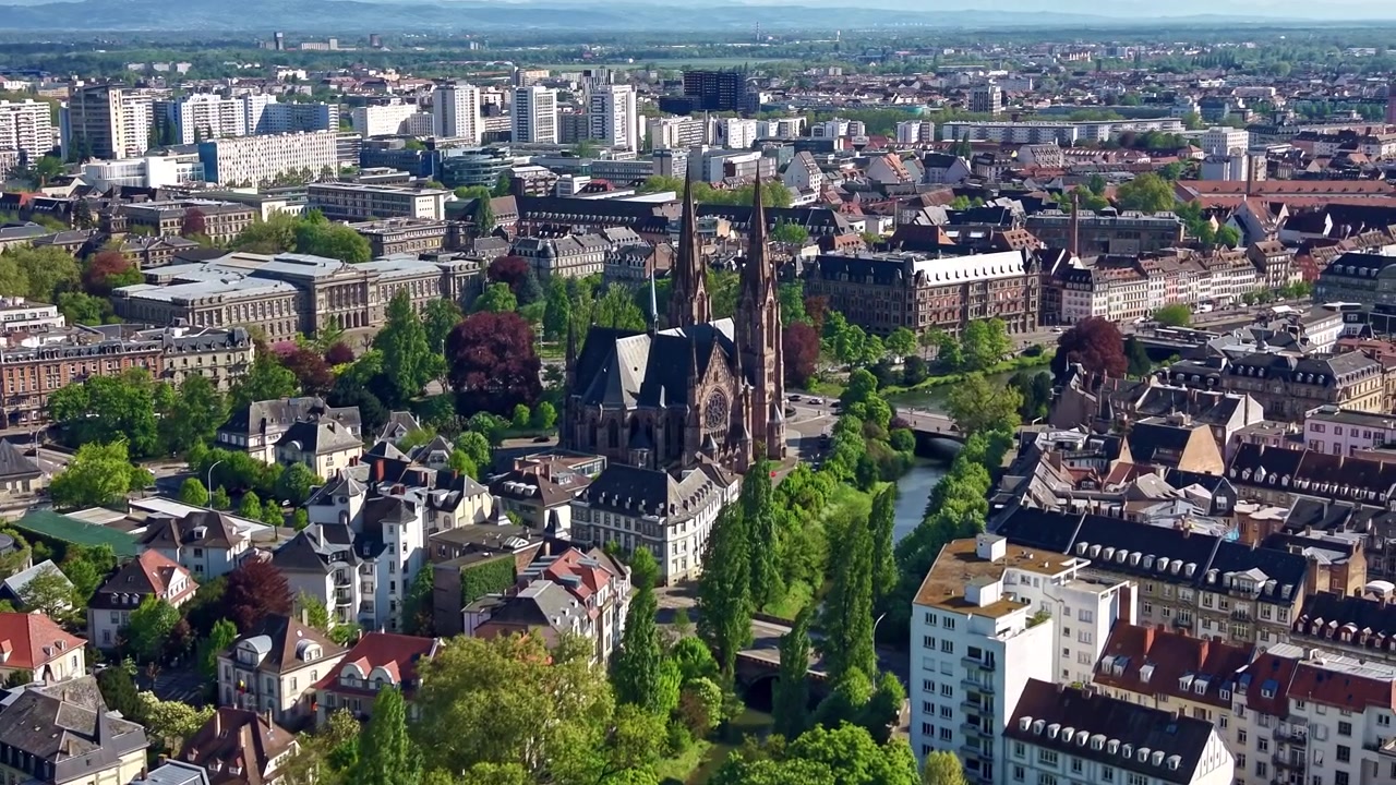 Drone panorerer sidelæns over Strasbourg og afslører Saint-Paul kirkens spir.