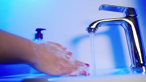 woman washing hands with soap over sink in bathroom, closeup