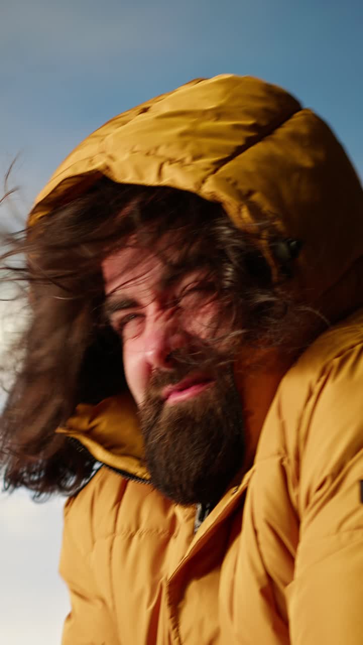 Hombre luchando contra el viento fuerte mientras intenta ponerse la capucha