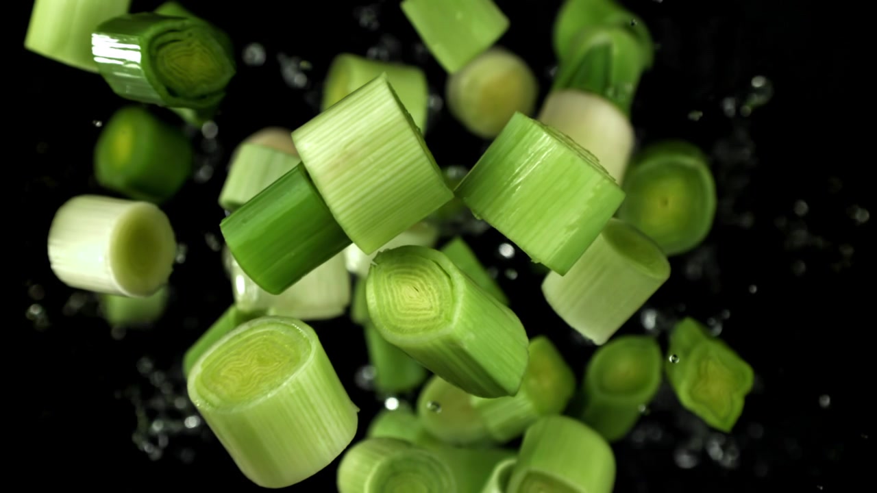 Fresh Chopped Leeks Falling with Water Splashes in Slow Motion