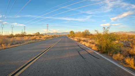 pov conduciendo en una carretera de asfalto y bajo líneas de transmisión de energía a través del desierto de sonora en el sur de arizona