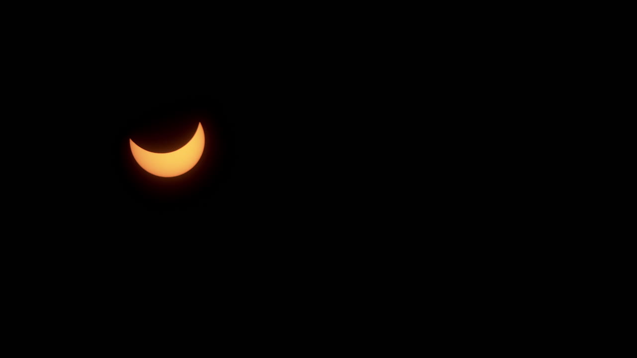 un sol creciente se mueve a través del cielo durante la fase parcial de un eclipse