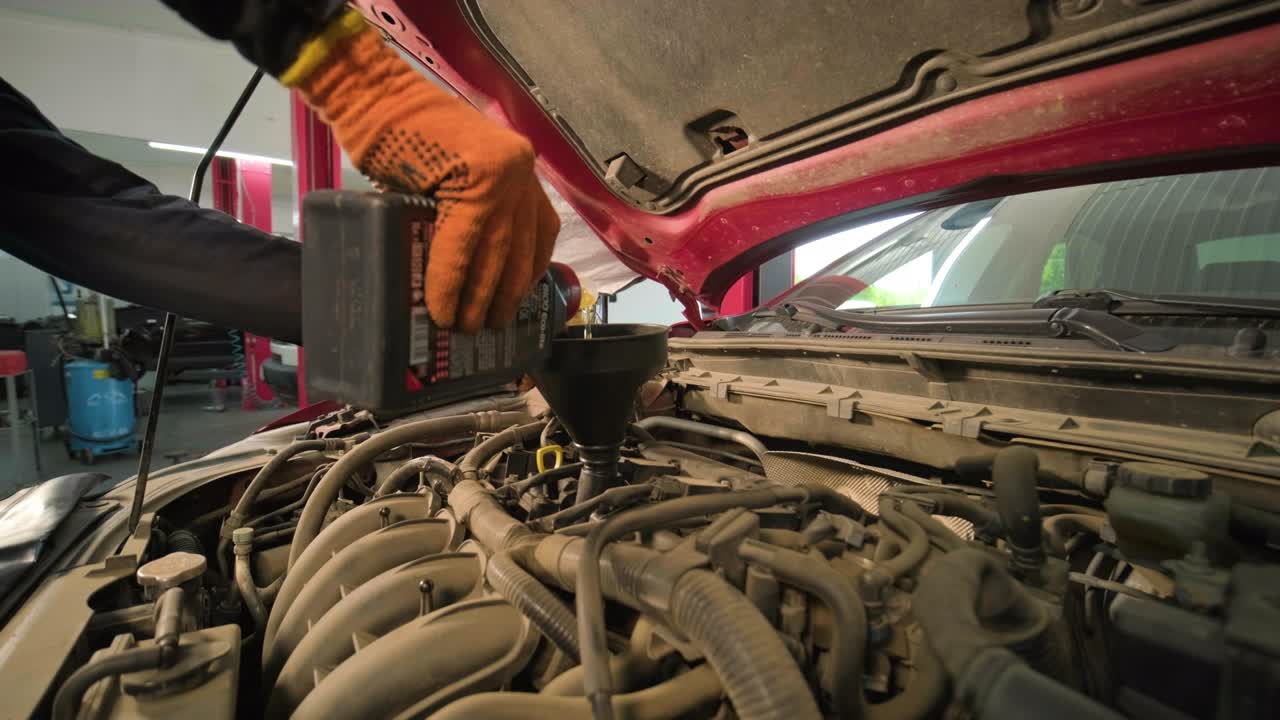 el mecánico de automóviles está cambiando el aceite del motor en un motor en la estación de automóviles.