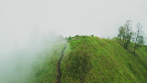 soft clouds hover over trunyan hill as drone footage reveals rich green mountain slopes and mist swirling gently, offering a tranquil and foggy view of bali’s natural beauty