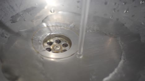 water running into a drain in a stainless steel sink