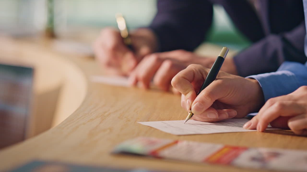 manos escribiendo papeles notas en el mostrador de recepción primer plano. huéspedes del hotel llenando