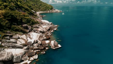 flying over amazing rocky beach and tropical lagoon with yacht