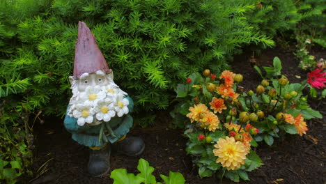 Un-Gnomo-De-Jardín-Con-Flores-Y-Rodeado-De-Arbustos-Afuera-En-Un-Jardín