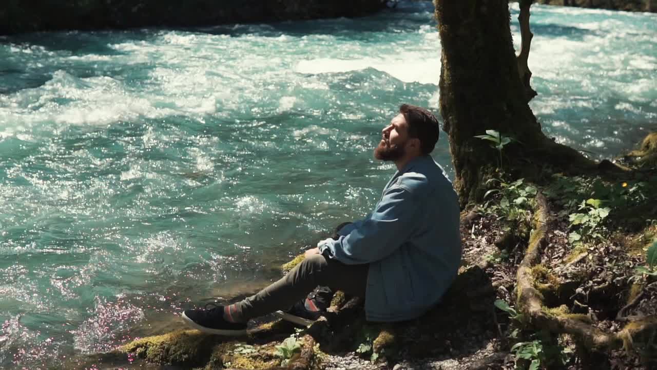 hombre meditando junto a un río en un bosque