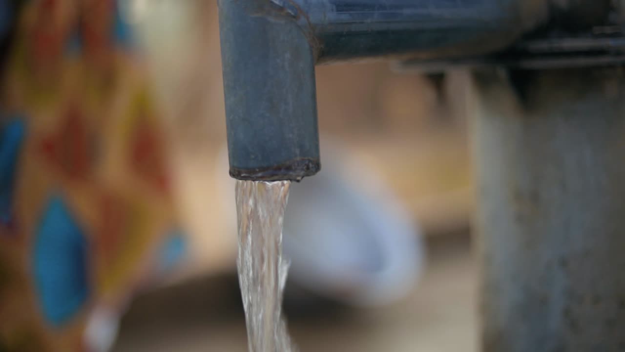 Water running from waterpump tap Africa clean drinking water from a traditional watertap - close up