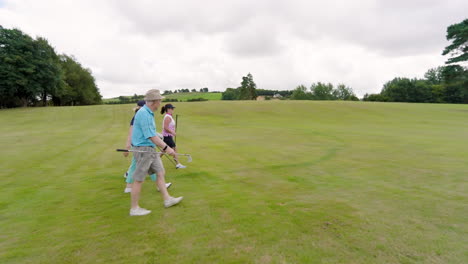 Male and female golf players walking with clubs and entering golf course, copy space