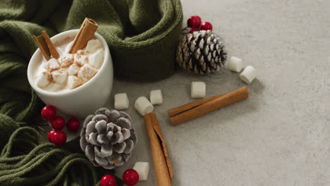 video of cup of hot chocolate with marshmallows and warm blanket over grey background