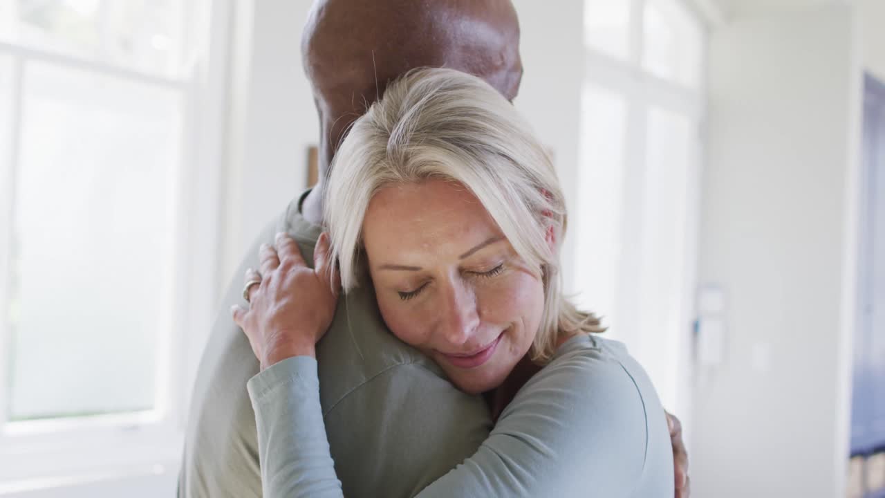 Mixed race senior couple hugging each other at home