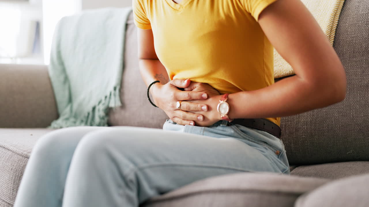 Dor, período menstrual e mãos de mulher sobre o estômago