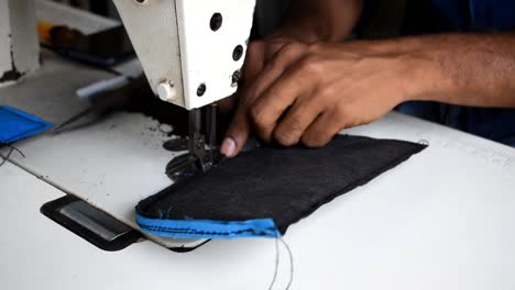 hands edging padding of a backpack bag with a sewing machine, close up