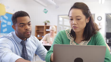 Teacher-helps-woman-using-laptop-at-an-adult-education-class