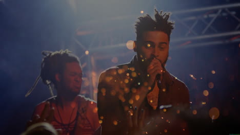 male singer and bassist performing on concert stage, with mic, animated spotlights, bokeh lights