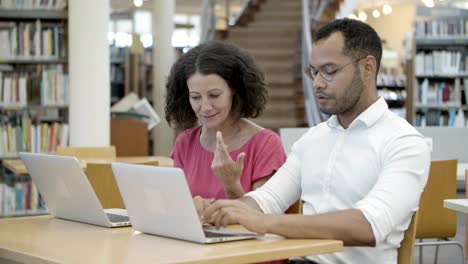 colegas emocionados discutiendo algunas preguntas en la biblioteca