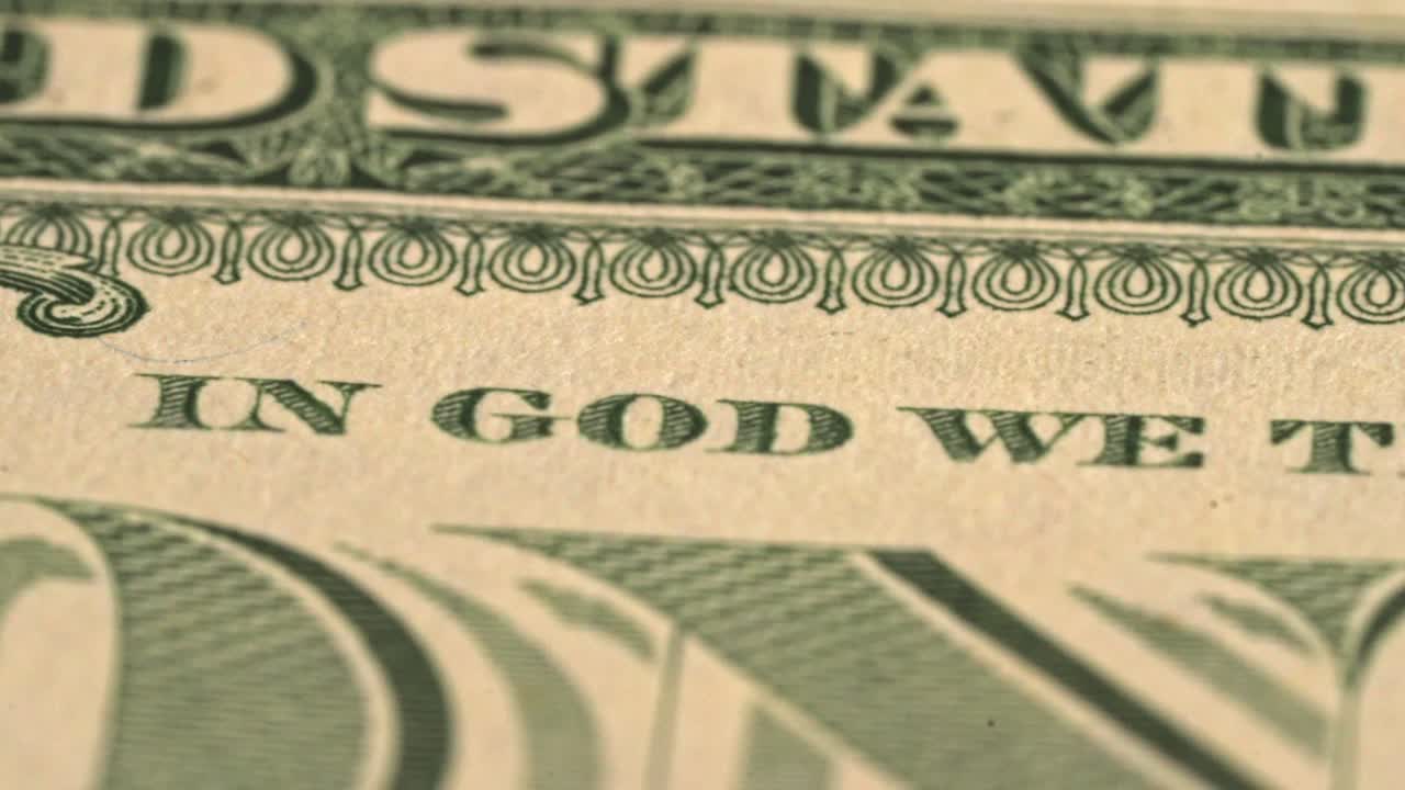 Close-up view of a dollar bill with a focus on the inscription