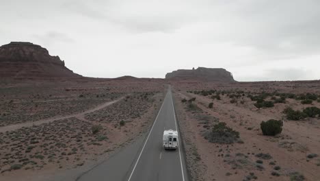 Seguimiento-De-La-Vista-Aérea-De-Una-Autocaravana-Que-Viaja-Por-La-Carretera-Del-Desierto-En-Monument-Valley-Park,-Utah,-EE.-UU.,-Que-Resume-La-Esencia-De-La-Vida,-Los-Viajes-Y-La-Exploración-En-Furgoneta.