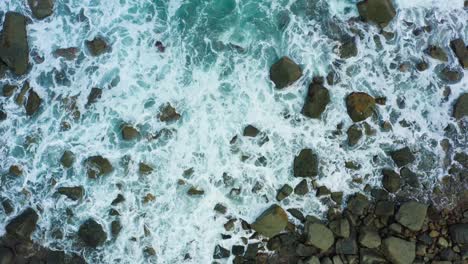 aerial view of waves crashing on the rock beach