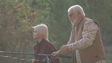 senior man teaches young woman how to fish