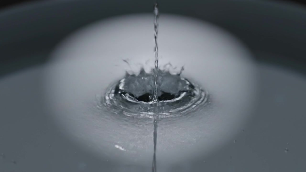 Primo piano di una goccia d'acqua che cade in un liquido, creando increspature