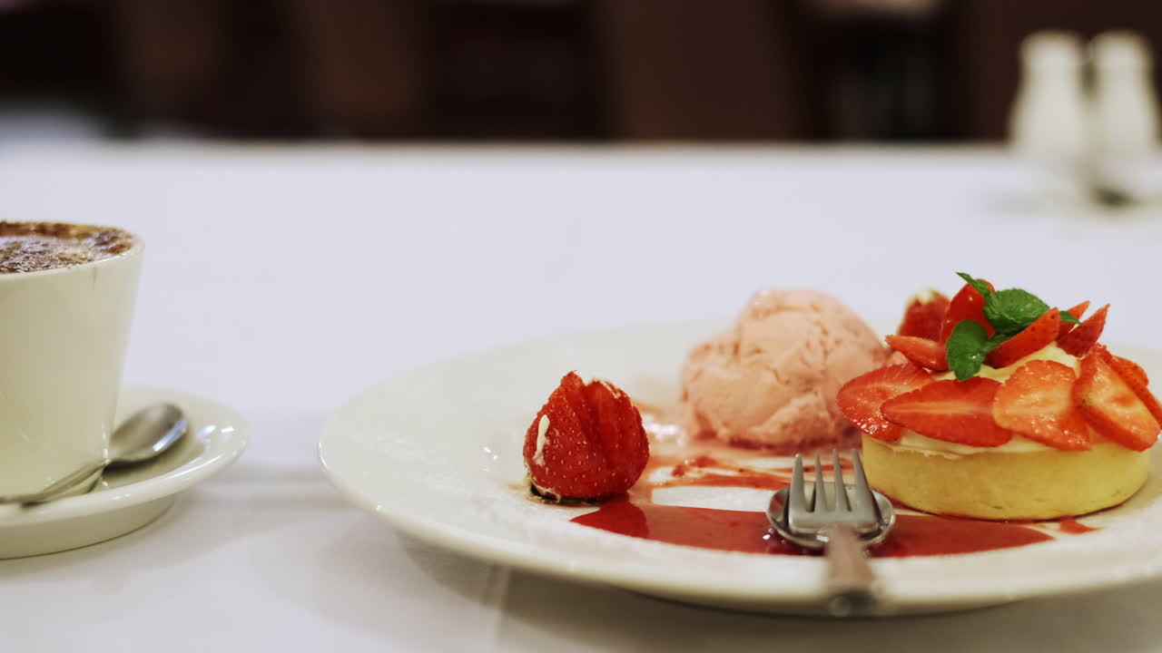 tentador postre de merengue, crema chantilly, compota de bayas mixtas y helado, junto a un capuchino