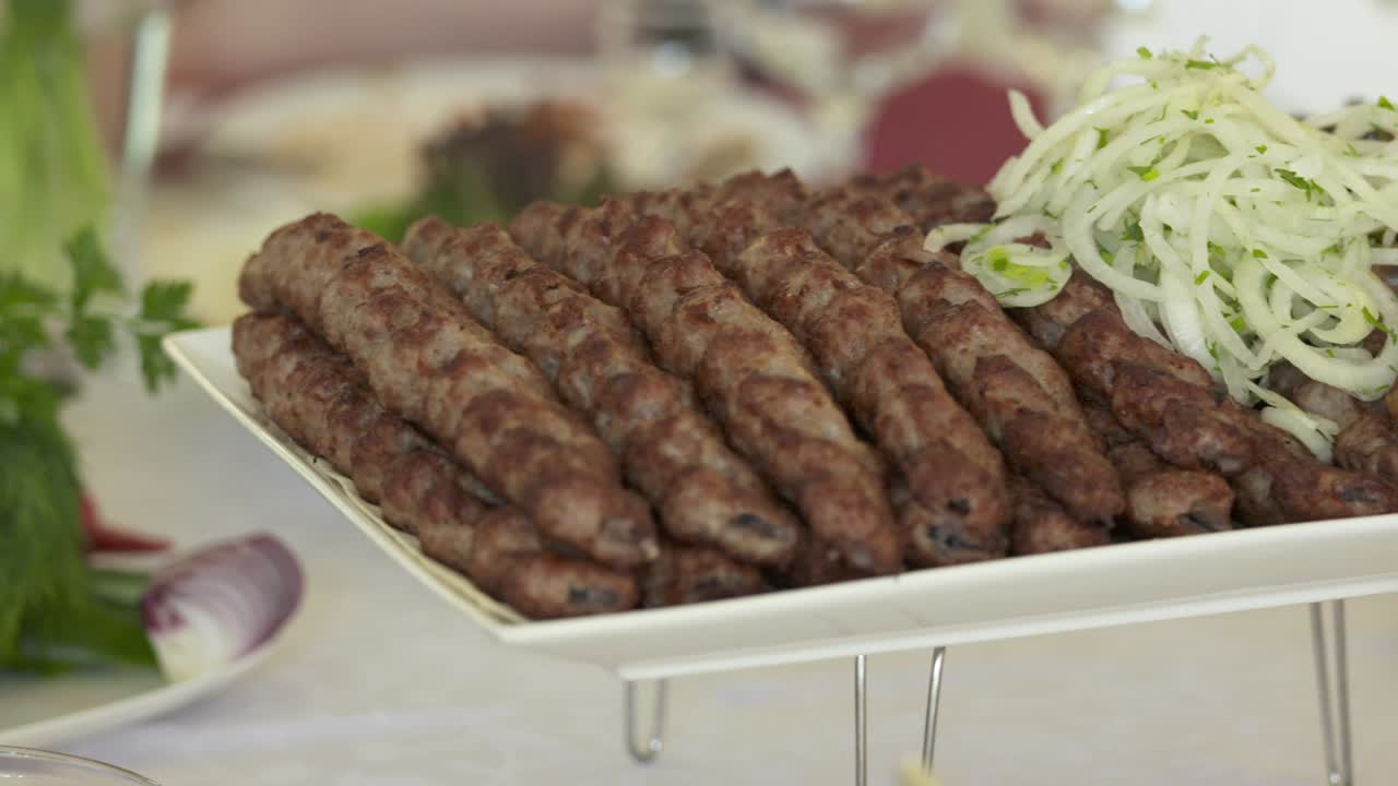 Kebab lula armenio servido en una fuente decorativa con cebolla picada.