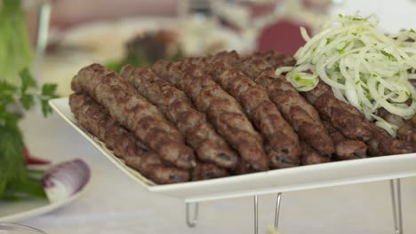 lula kebab armenio servido en una bandeja decorativa con cebolla picada