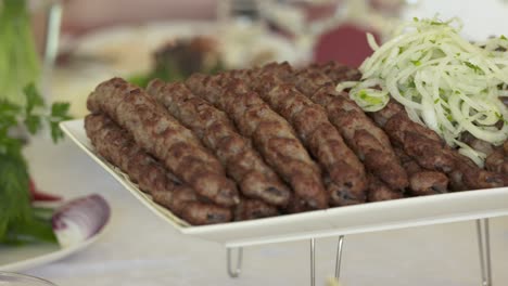 armenian lula kebab served on decorative platter with chopped onion