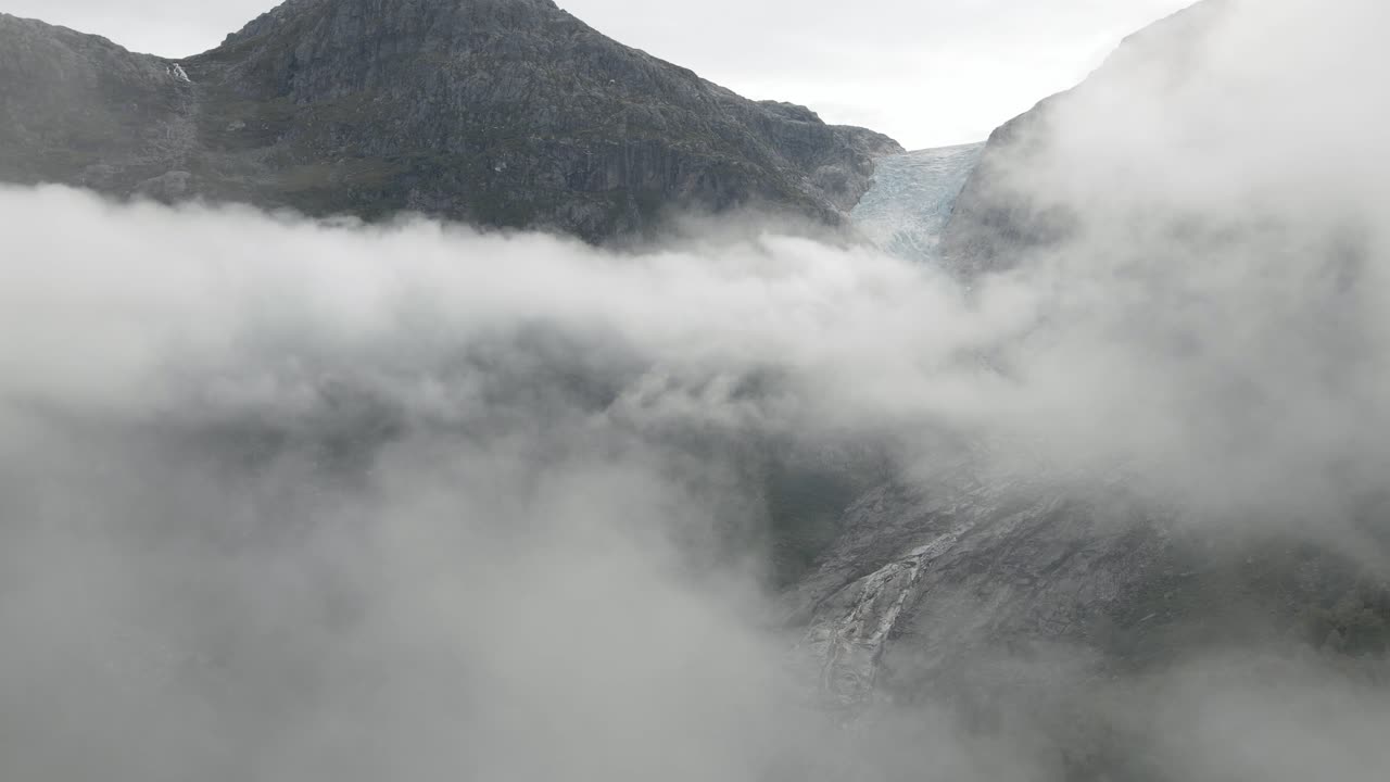 장엄한 빙하, 공중 드론 샷으로 클라우드 스케이프 위에 서있는 바위 산