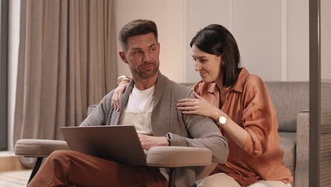 woman helping man working on laptop