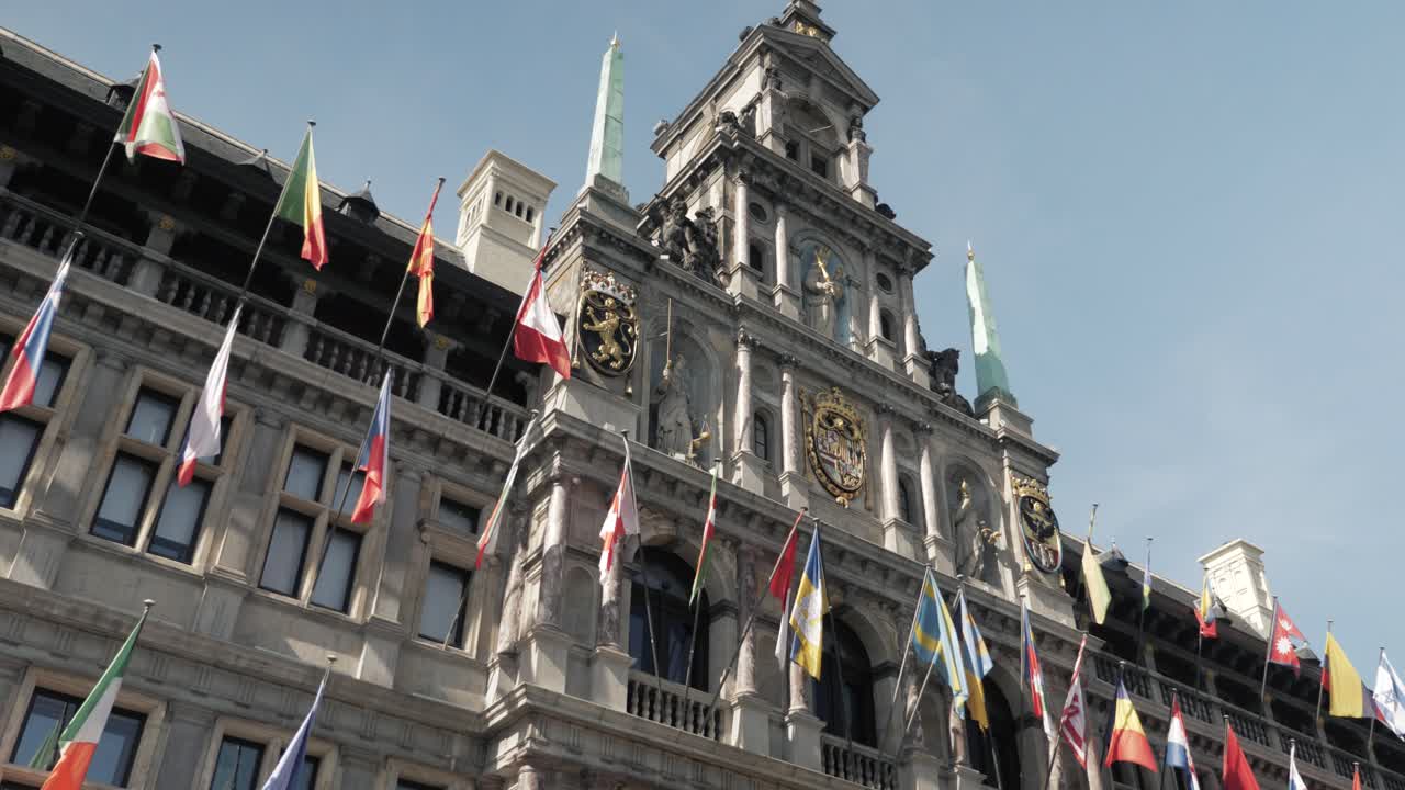 Architectural shot of Antwerp City Hall with international flags on a sunny day