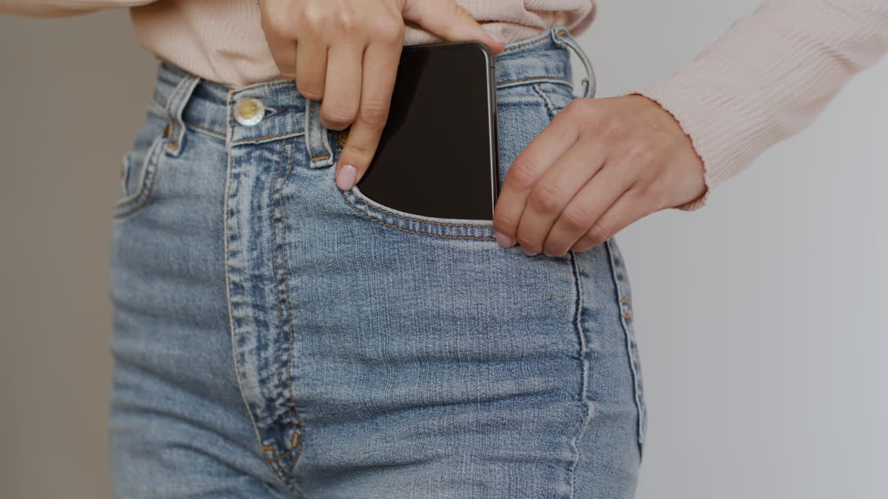 Woman putting a phone into jeans pocket