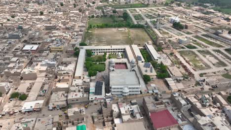 Aerial-zoom-out-of-Darul-Uloom-Hussainia-amidst-the-urban-grid-of-Shahdadpur,-Sindh