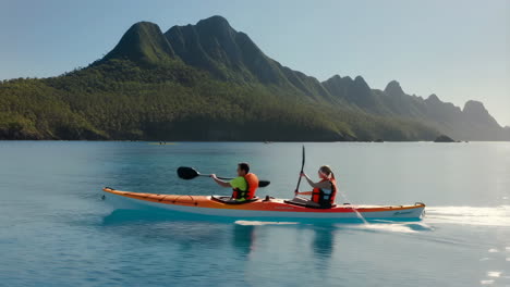 couple kayaking on calm water with scenic mountains in background
