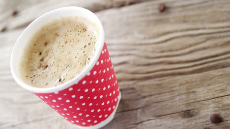 granos de café cayendo en una taza desechable