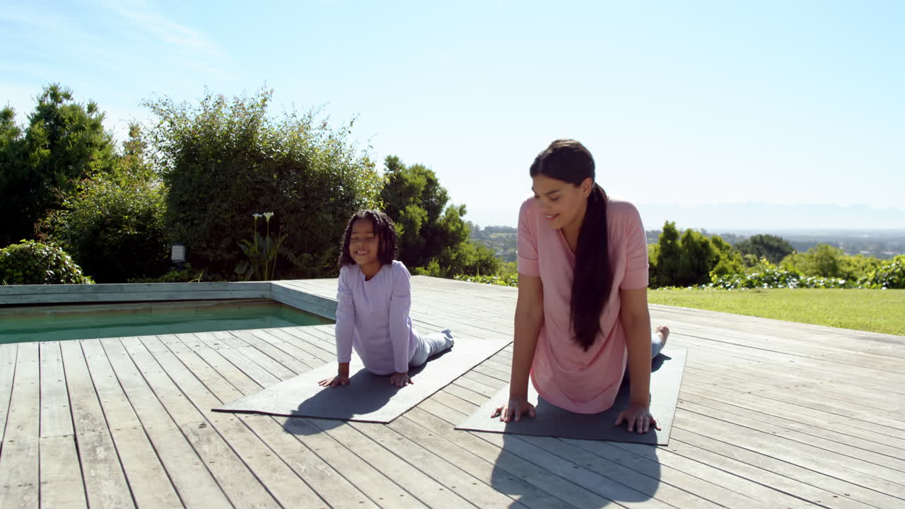 Mother and daughter practicing yoga on deck, enjoying sunny outdoor exercise