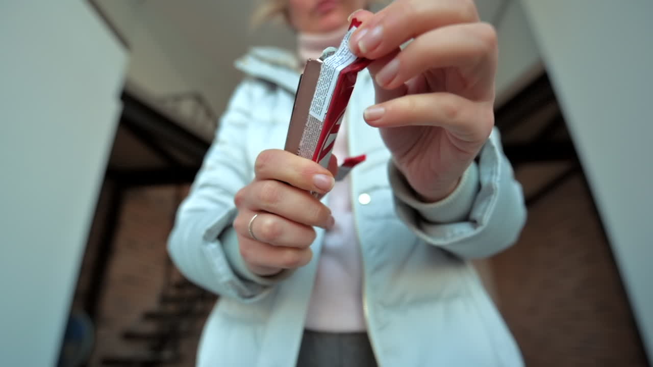 Woman opening a chocolate covered wafer bar in slow motion
