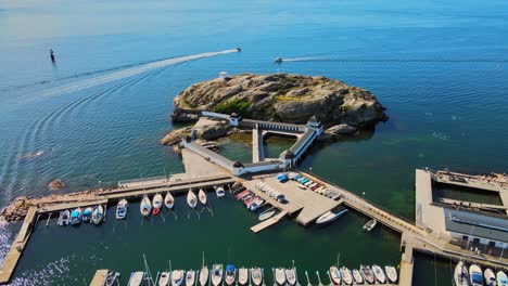 volando sobre barcos amarrados en el puerto deportivo hacia la isla de slaggo y kallbadhuset, centro acuático en lysekil, suecia