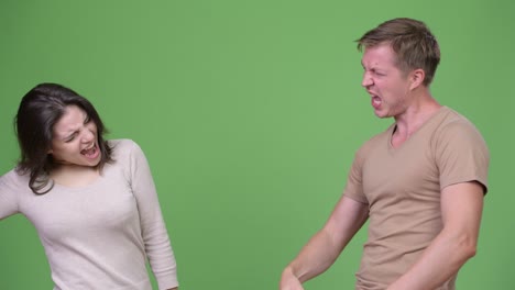 young couple giving high-five together against green background