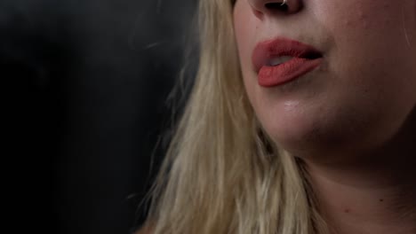 disparo en cámara lenta de una chica soplando humo de cigarrillo de su boca